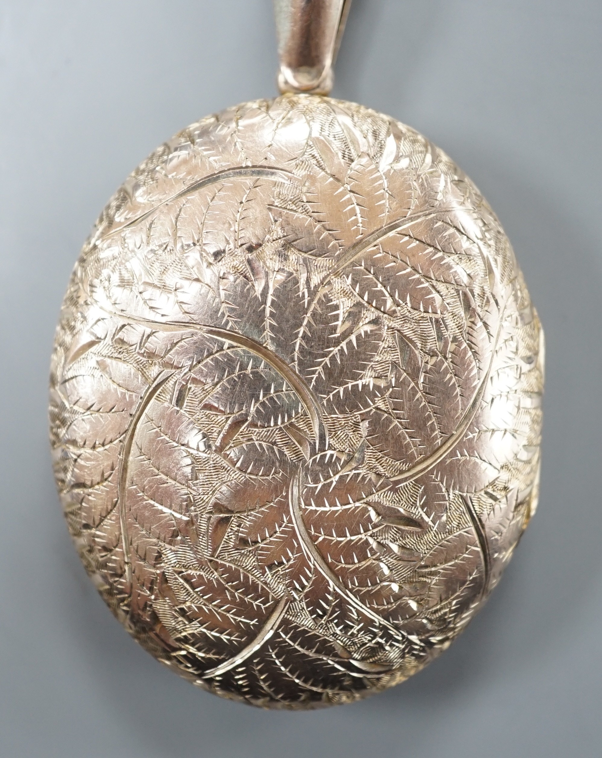 An engraved yellow metal overlaid oval locket, 46mm.